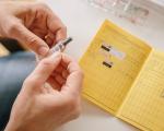 Hand hält Impfdosis mit Impfpass im Hintergrund - Wer nach Sansibar reist, muss ab sofort eine Gelbfieber-Impfung nachweisen.