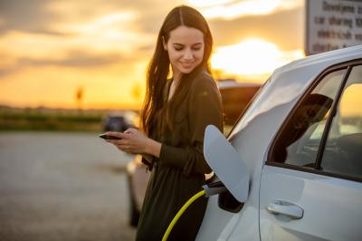 Mit CHECK24 können Sie Mietpreise für E-Autos vergleichen Frau lädt Elektroauto